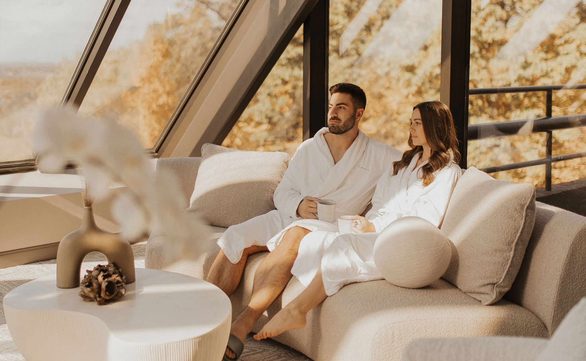 Spa at Woodcliff relaxation lounge in fall Couple in robes relaxing in the Spa at Woodcliff lounge with fall foliage outside the glass walls
